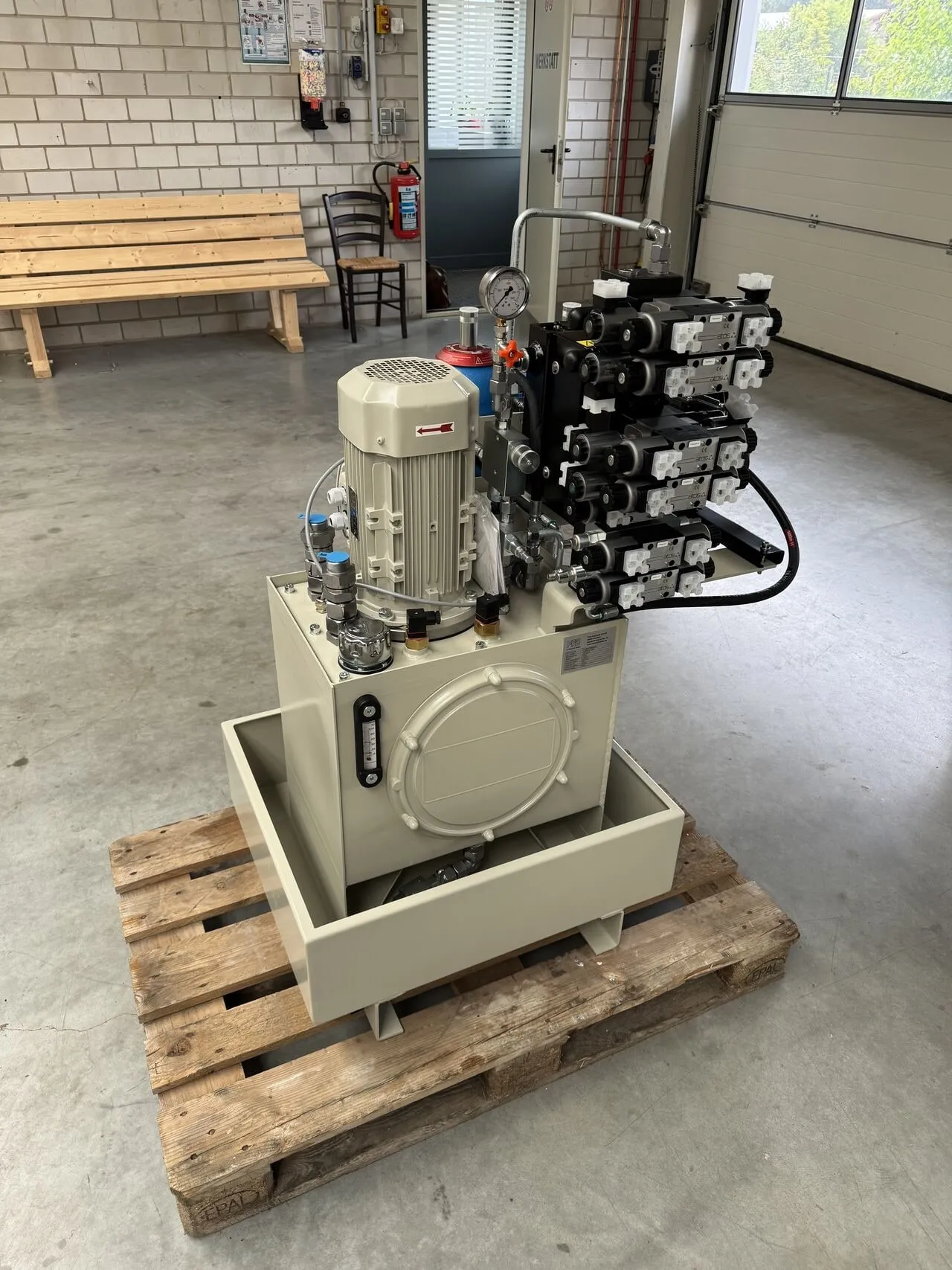 Hydraulikaggregat mit zehn Wegeventilen und Druckspeicher auf engem Bauraum, beige lackiert